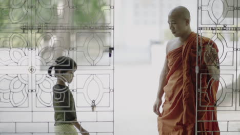 Männlicher-Burmesischer-Mönch-Mit-Traditioneller-Kleidung-öffnet-Eine-Tür,-Um-Ein-Weibliches-Kind-Hineinzulassen