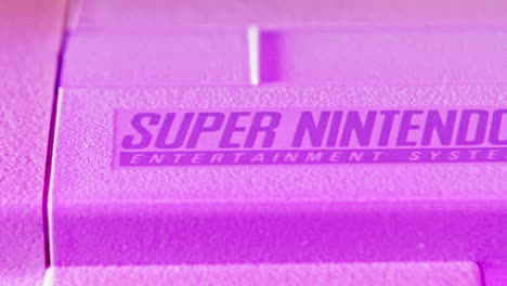 Logo-on-Vintage-Super-Nintendo-Console-in-Purple-Light-SLIDE-LEFT