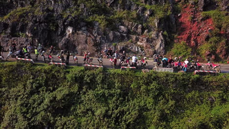 Drone-side-view-of-a-group-of-motorcyclists-resting-on-the-side-of-the-road,-along-the-Ma-Pi-Leng-Pass-in-the-late-afternoon