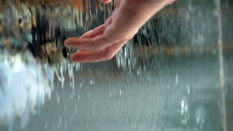 Man-runs-his-hand-through-the-water-at-the-water-window-of-the-National-Art-Gallery-of-Victoria