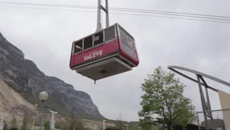Salève-cable-car-leaving-the-bottom-station-up-to-the-top-on-overcast-day,-panning-shot