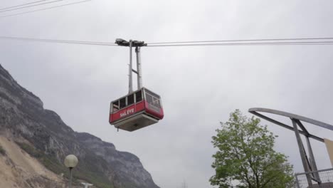 Salève-cable-car-coming-down-on-overcast-day,-panning-low-angle-shot