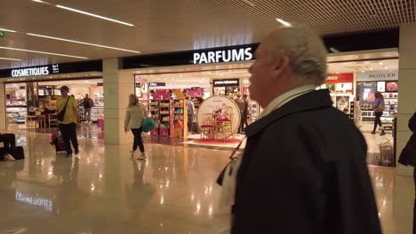 Passagiere-Im-Inneren-Des-Flughafens-Orly-Auf-Dem-Weg-Zum-Boarding-Und-Passieren-Vor-Den-Duty-Free-Shops