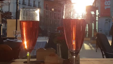 Sunrays-hitting-sparkling-Rosé-wine-at-outside-terrace-restaurant-in-Madrid,-festive-bubbles-rising