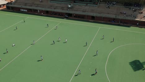 A-diagonal-pan-right-drone-shot-of-a-field-hockey-game-under-sunny-conditions