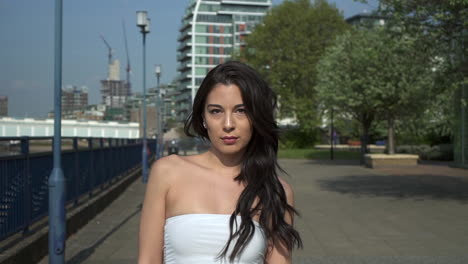 Attraktive-Und-Verspielte-Hispanische-Latina-Frau,-Die-Auf-Die-Kamera-Zugeht,-Am-Ufer-Der-Themse-In-London,-Großbritannien