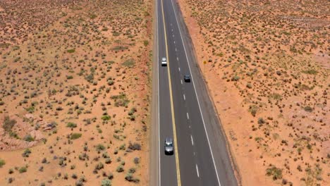 Aerial-drone-footage-of-cars-driving-on-road-in-the-middle-of-the-desert-in-Arizona,-USA