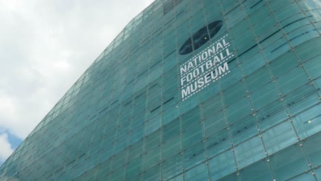 National-Football-Museum-sign-on-side-of-building-tourist-attraction-public-location-Greater-Manchester-City-Summer-Sunny-Day-Tourist-Attraction-Landmark-Wider-Angle-4K-25p