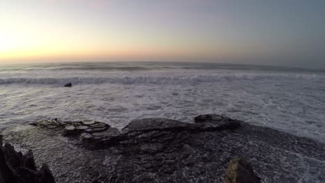 early-morning-at-the-sea-with-waves-crashing-onto-a-rocky-coastline