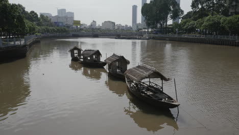 Toma-Aérea-De-Una-Fila-De-Viejos-Barcos-De-Pesca-Fluviales-De-Estilo-Tradicional-En-Un-Canal-Hoang-Sa-En-El-Distrito-De-Binh-Thanh-De-La-Ciudad-De-Ho-Chi-Minh-O-Saigon-Vietnam