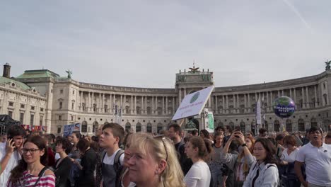 Slow-right-pan-over-crowds-gathered-during-protests-in-Vienna,-with-backdrop-of-national-library