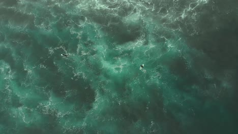 Aerial-Shot-of-two-Surfers-chilling-on-turquoise-water-from-above,-Pichilemu,-CHile-4K