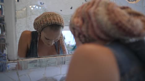 A-young,-alternative-woman-with-tattoos-is-holding-her-arms-over-her-head-while-looking-at-her-reflection-in-the-mirror