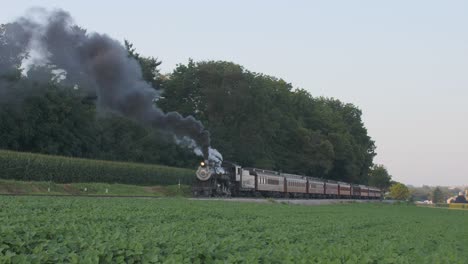 A-1924-Steam-Engine-with-Passenger-Train-Puffing-Smoke-Traveling-Along-the-Amish-Countryside-on-a-Summer-Day