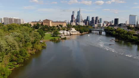Low-aerial-drone-above-Schuylkill-River-with-Philadelphia-skyline-on-bright-sunny-summer-day
