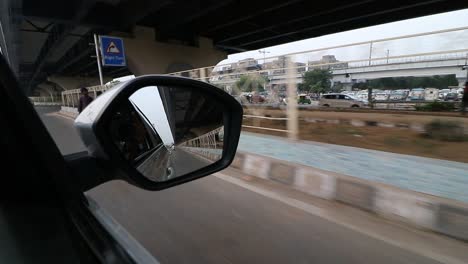 Mirror-view-of-flyover-from-a-moving-vehicle-in-New-Delhi,-India