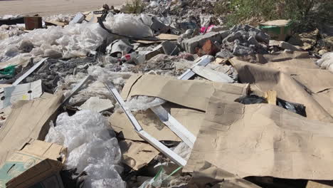 Strewn-Plastic,-Packaging,-Cardboard,-Trash,-Rubbish-Pile-DIAGONAL-PAN