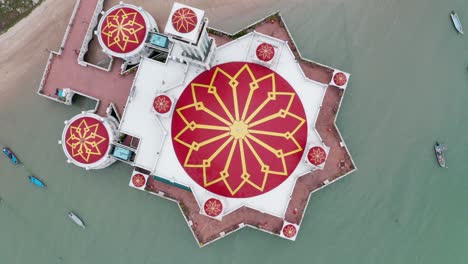 Tanjung-Bunga-floating-mosque-is-seen-from-directly-above-with-massive-red-dome,-Aerial-drone-lift-up-rotating-shot