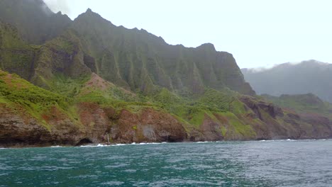 4K-Hawaii-Kauai-Boating-on-ocean-floating-left-to-right-with-waves-crashing-along-mountain-shoreline