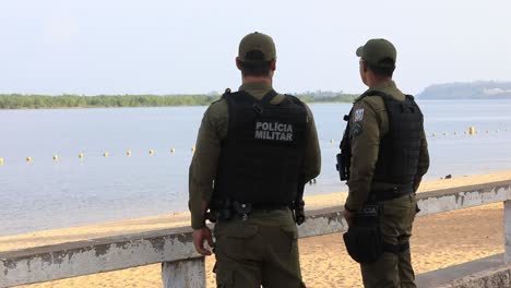 Zwei-Militärpolizisten-Stehen-Da-Und-Unterhalten-Sich-Beiläufig,-Während-Sie-Am-Strand-Patrouillieren