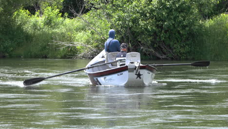 Two-men-rowing-small-boat-across-fast-flowing-river