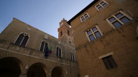 Wide-dolly-shot-of-bulidings-at-Piazza-Pio-secondo,-Pienza,-Tuscany-on-sunny-day