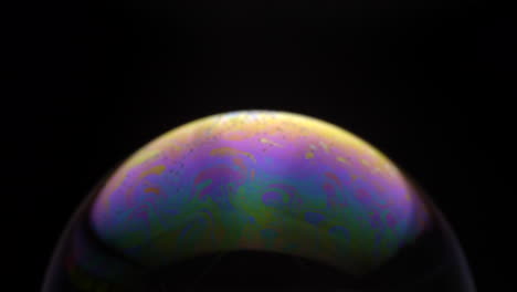 Liquid-Soap-Bubble-With-Multicolored-Surface-On-Black-Background