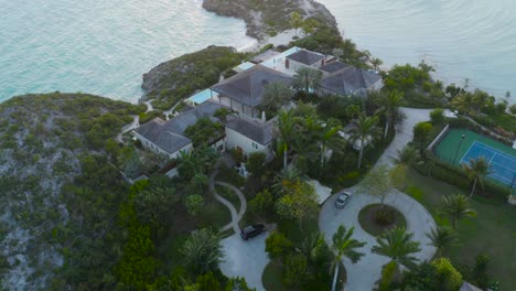 Aerial-View-of-a-beautiful-villa-with-pool-and-palm-trees-in-seashore-of-Turk-And-Caicos-Caribbean,-4K