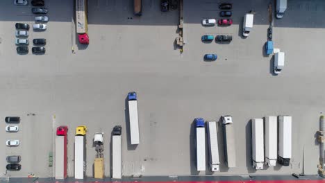 Cargo-Truck-Maneuvering-Backwards-At-The-Docking-Area-Of-A-Warehouse-In-Kowale,-Gdansk-County,-Poland---aerial-shot
