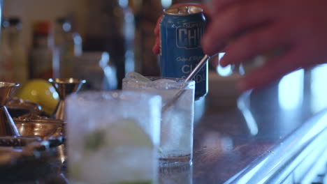 Hands-pouring-soft-drinks-into-cocktail-glasses-on-a-bar,-slow-motion