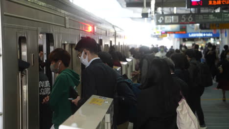 Pasajeros-Con-Mascarilla-Subiendo-Al-Metro-Durante-La-Hora-Pico-En-Tokio,-Japón