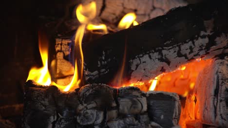 Close-up-view-of-campfire-of-Aspen-made-of-logs-burning-focusing-on-the-coals,-with-yellow-flames,-stationary-shot-with-no-movement