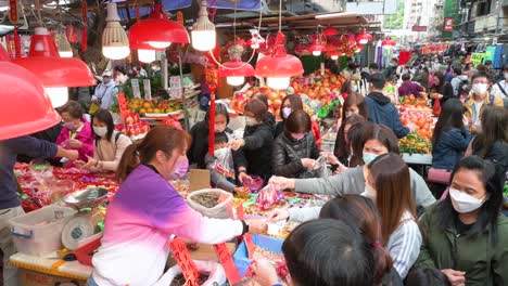 Customers-shop-for-fruits,-food,-and-candies-at-street-market-stalls-for-the-upcoming-Chinese-Lunar-New-Year-festivities-and-celebrations-in-Hong-Kong