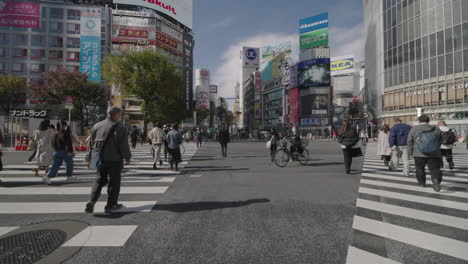 People-Cross-At-Famous-Shibuya-Scramble-Crossing-Near-Shopping-District-On-A-Sunny-Day-At-City-Of-Tokyo,-Japan-During-Pandemic