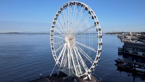 The-Great-Wheel-of-Seattle-on-the-calm-blue-waters-of-Elliot-Bay,-aerial-orbit