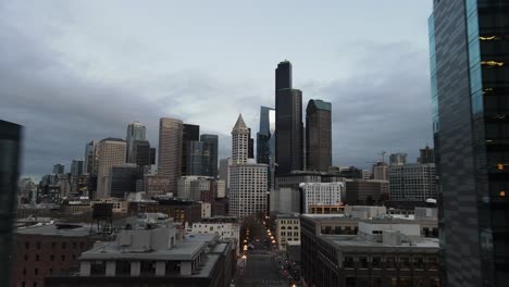 Gray-skies-hang-over-an-early-morning-Seattle-city-skyline,-aerial-pull