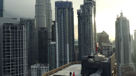 Happy-Tourists-Running-On-A-Rooftop-At-Sunset-In-Kuala-Lumpur,-Breathtaking-City-Scene