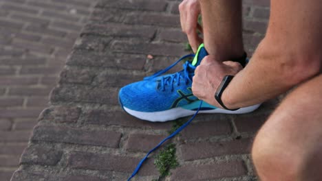 Closeup-andfocus-on-hands-of-trail-runner-untie-and-tying-shoe-laces-securely-before-a-run-wiping-off-the-specialised-gear