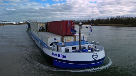 Aerial:-circling-around-a-loaded-containership-navigating-through-the-canal-of-Zwijndrecht,-The-Netherlands