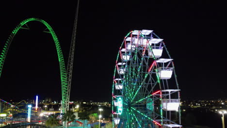 Aerial-view-around-a-ferris-wheel-at-a-theme-park,-night-in-Orlando,-Florida---orbit,-drone-shot