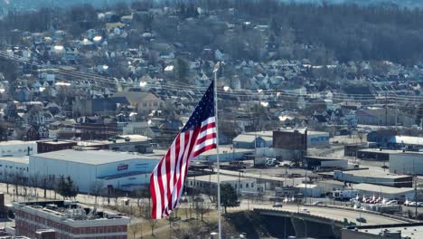 Long-aerial-zoom-of-American-flag-waving-in-front-of-winter-scenery-in-small-town-in-America