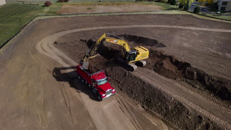 Una-Excavadora-Y-Un-Camión-Volquete-Trabajan-Juntos-En-Un-Sitio-De-Construcción