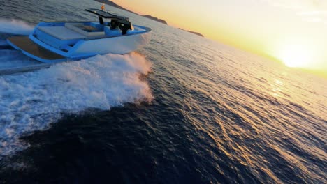 Scenic-FPV-aerial-following-a-luxury-yacht-sailing-into-the-sunset-off-the-coast-of-Ibiza,-Spain