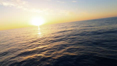 FPV-aerial-following-a-luxury-yacht-sailing-into-a-beautiful-Mediterranean-sunset-off-the-coast-of-Ibiza,-Spain
