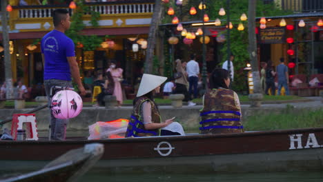 Tourists-taking-lantern-boat-ride-on-Hoai-river-in-Sampan-boat-in-ancient-town-of-Hoi-An-at-evening,-Vietnam