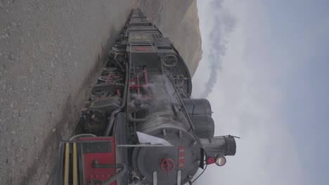 A-vintage-steam-engine-locamotive-in-Patagonia,-Argentina-with-mountains-in-the-background