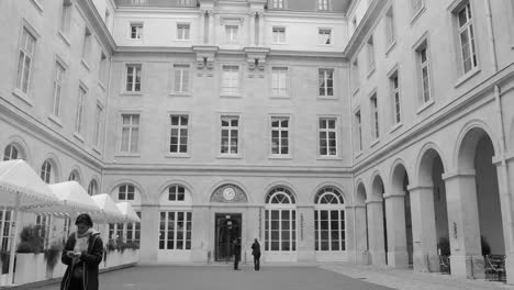 Monochrome-Of-People-Walking-Around-The-Inner-Courtyard-Of-Hotel-de-la-Marine-In-Paris,-France