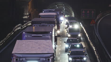 Long-telephoto-shot-of-busy-heavy-traffic-vehicles-exiting-tunnel,-driving-slow