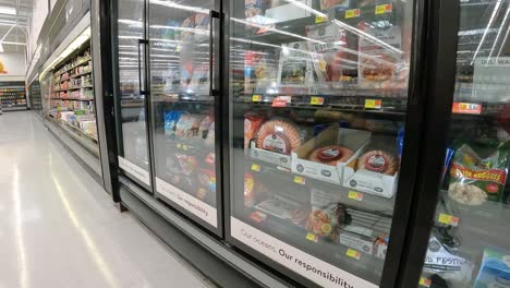 Empujando-Lentamente-Un-Carrito-De-Supermercado-Más-Allá-De-Las-Exhibiciones-De-Mariscos-Congelados-En-Una-Mega-Tienda-De-Comestibles-Americana