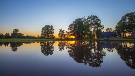Wunderschöner-Goldener-Sonnenuntergang-An-Einem-See-Mit-Einem-Abgelegenen-Haus-In-Lettland,-Zeitraffer